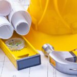 Hammer und Bauarbeiterhelm und Architektenpläne