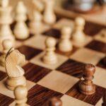 Holzschachfiguren auf einem Schachbrett als Symbol für Strategie und Taktik beim Bieterverfahren im Immobilienkauf | Bieterverfahren