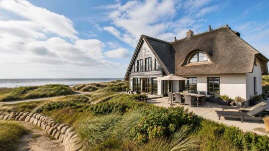 Ferienhaus mit Reetdach in Dünenlage am Meer – Symbolbild für den Verkauf einer Ferienimmobilie. | Immobilienverkauf