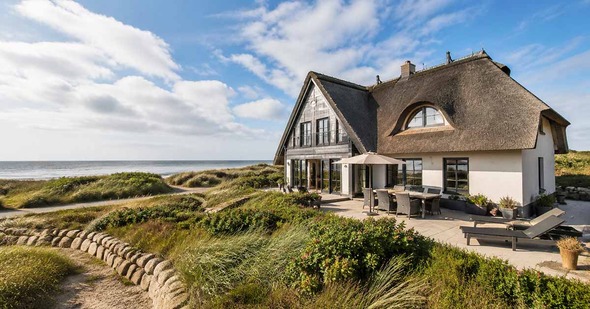 Ferienhaus mit Reetdach in Dünenlage am Meer – Symbolbild für den Verkauf einer Ferienimmobilie. | Immobilienverkauf